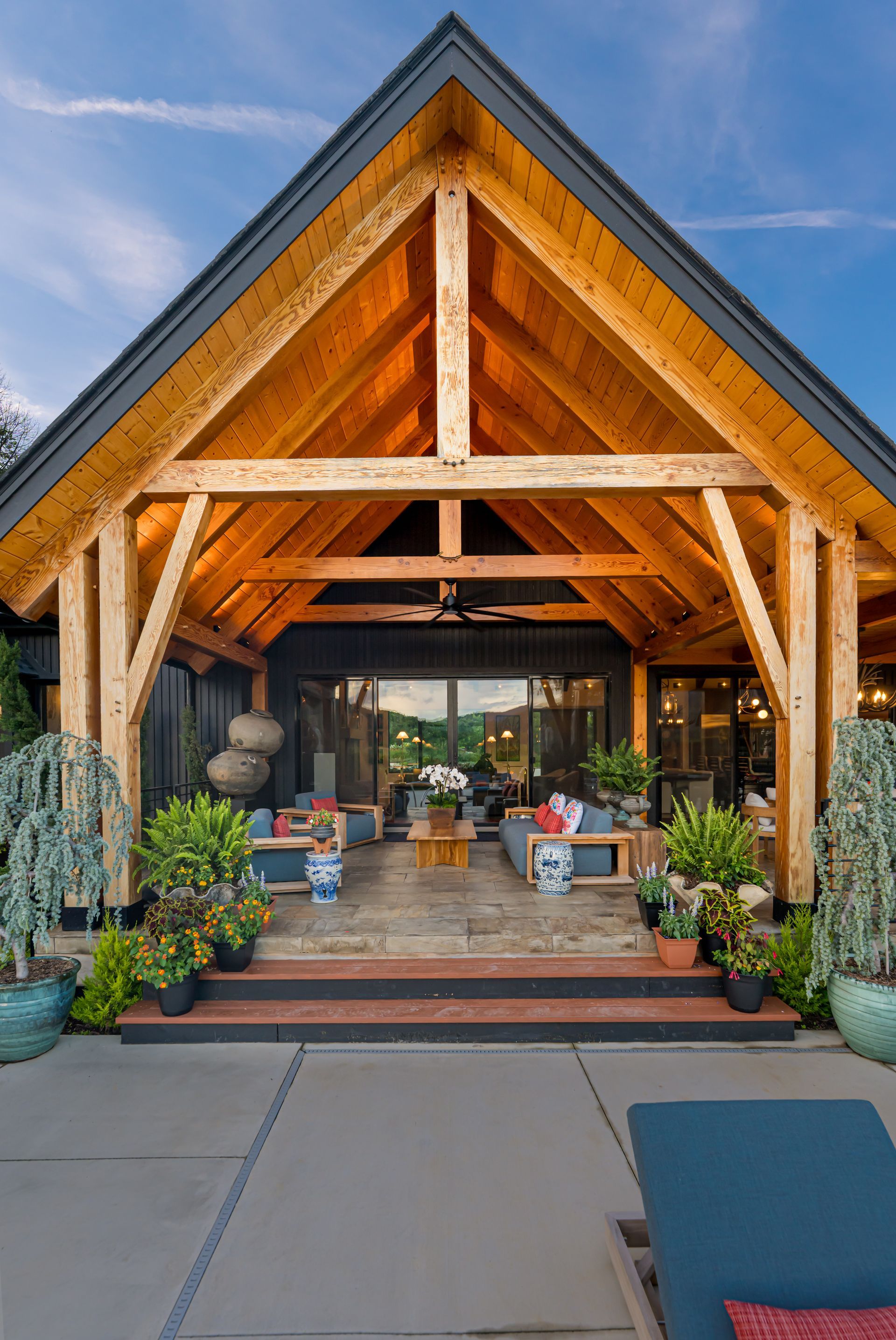 Wooden lodge entrance with potted plants, brick steps, and a patio under a peaked roof