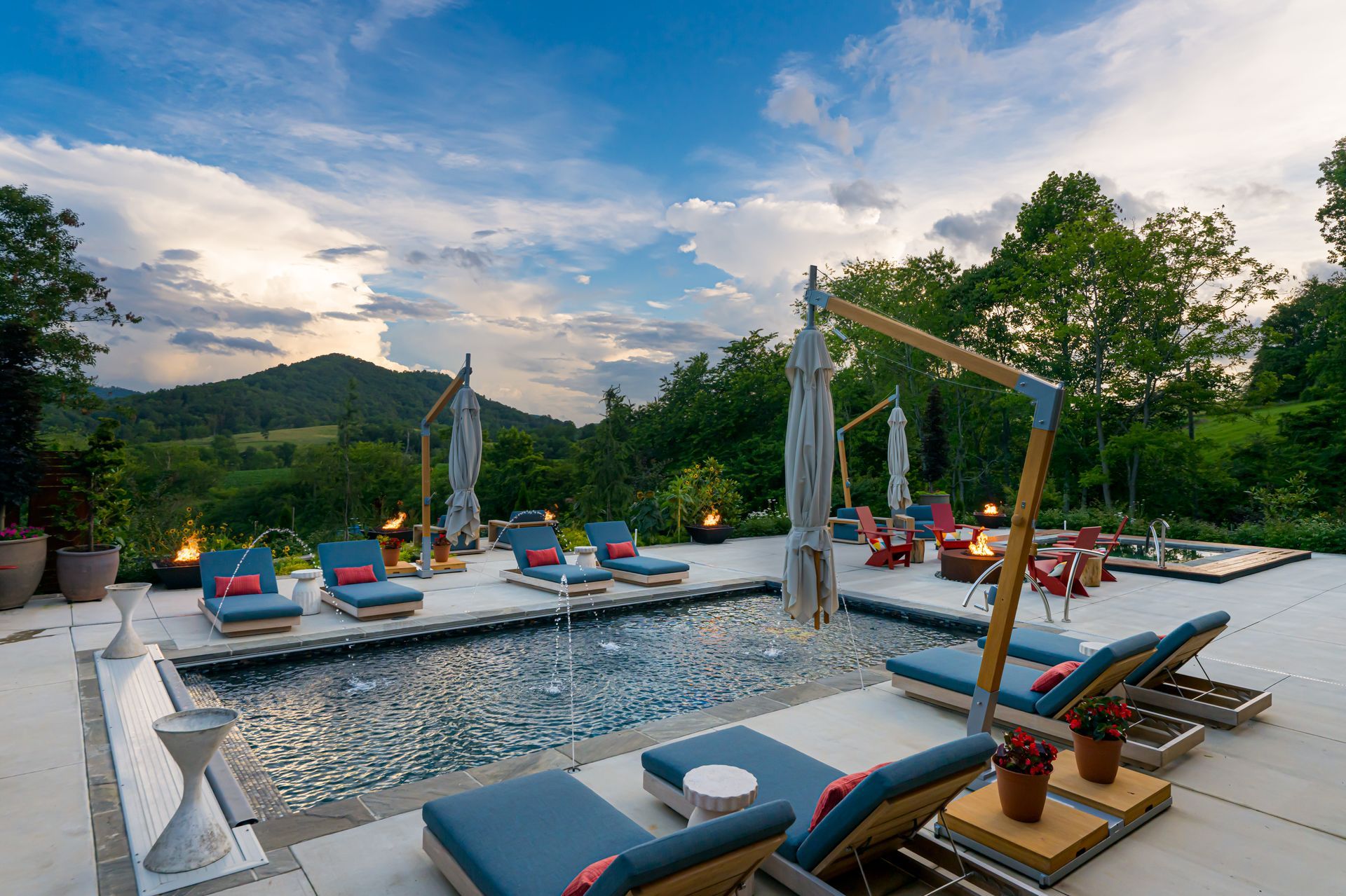 Luxury poolside lounge at sunset with blue daybeds, cabanas, and mountain views