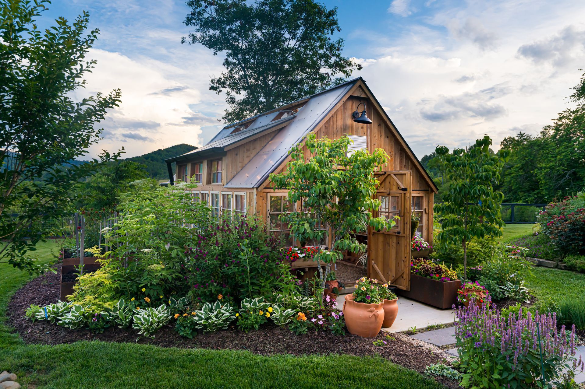 Cozy wooden cottage with a lush flower garden and greenery under a cloudy sky