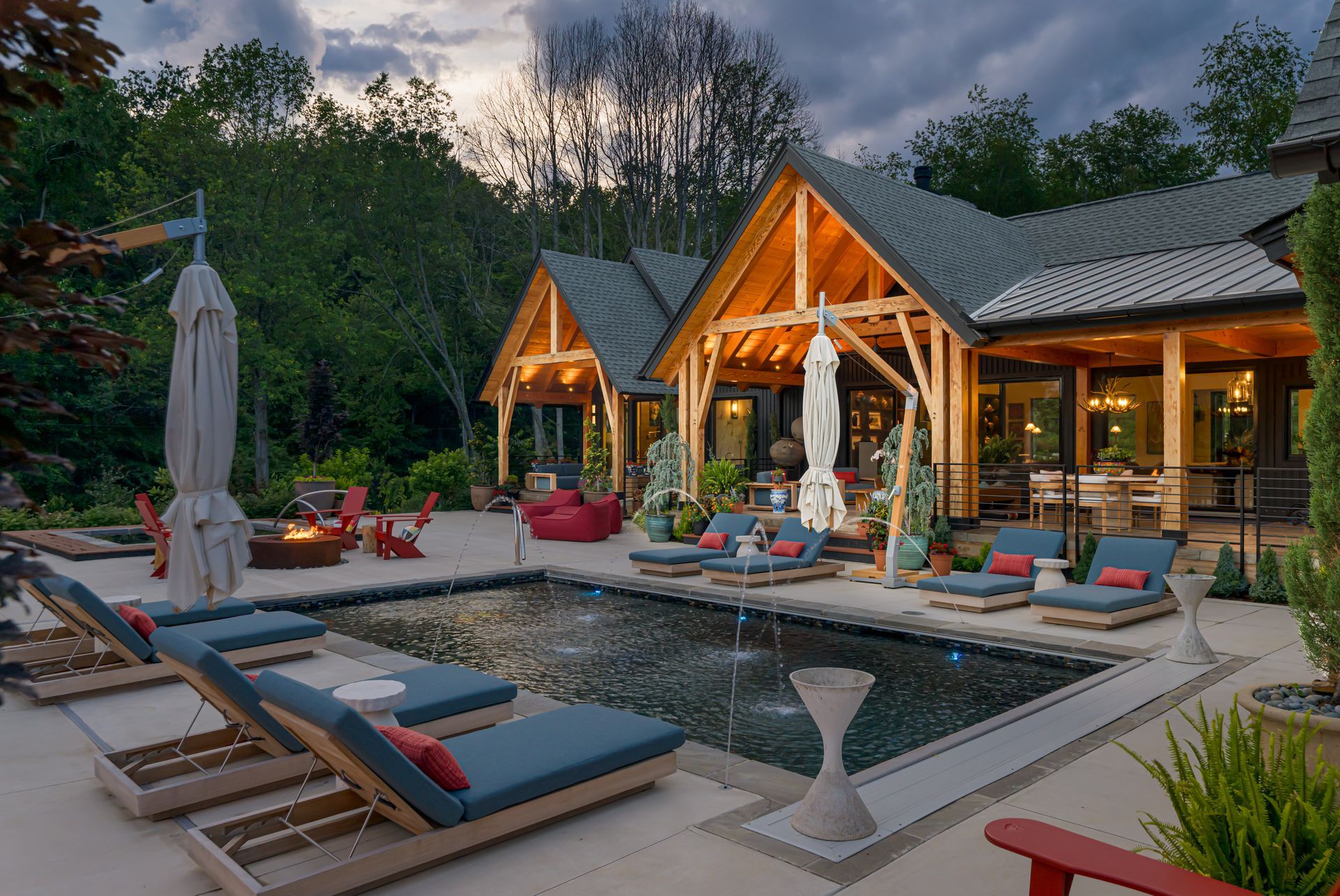 Modern luxury backyard with pool, lounge chairs, cabanas, and warm-lit patio at dusk