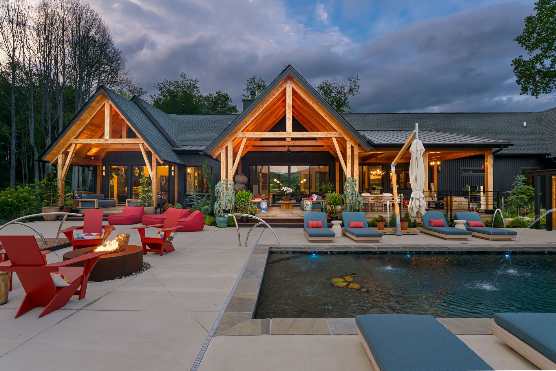 Luxury resort patio with red lounge chairs, lit cabanas, and a reflecting pool at dusk