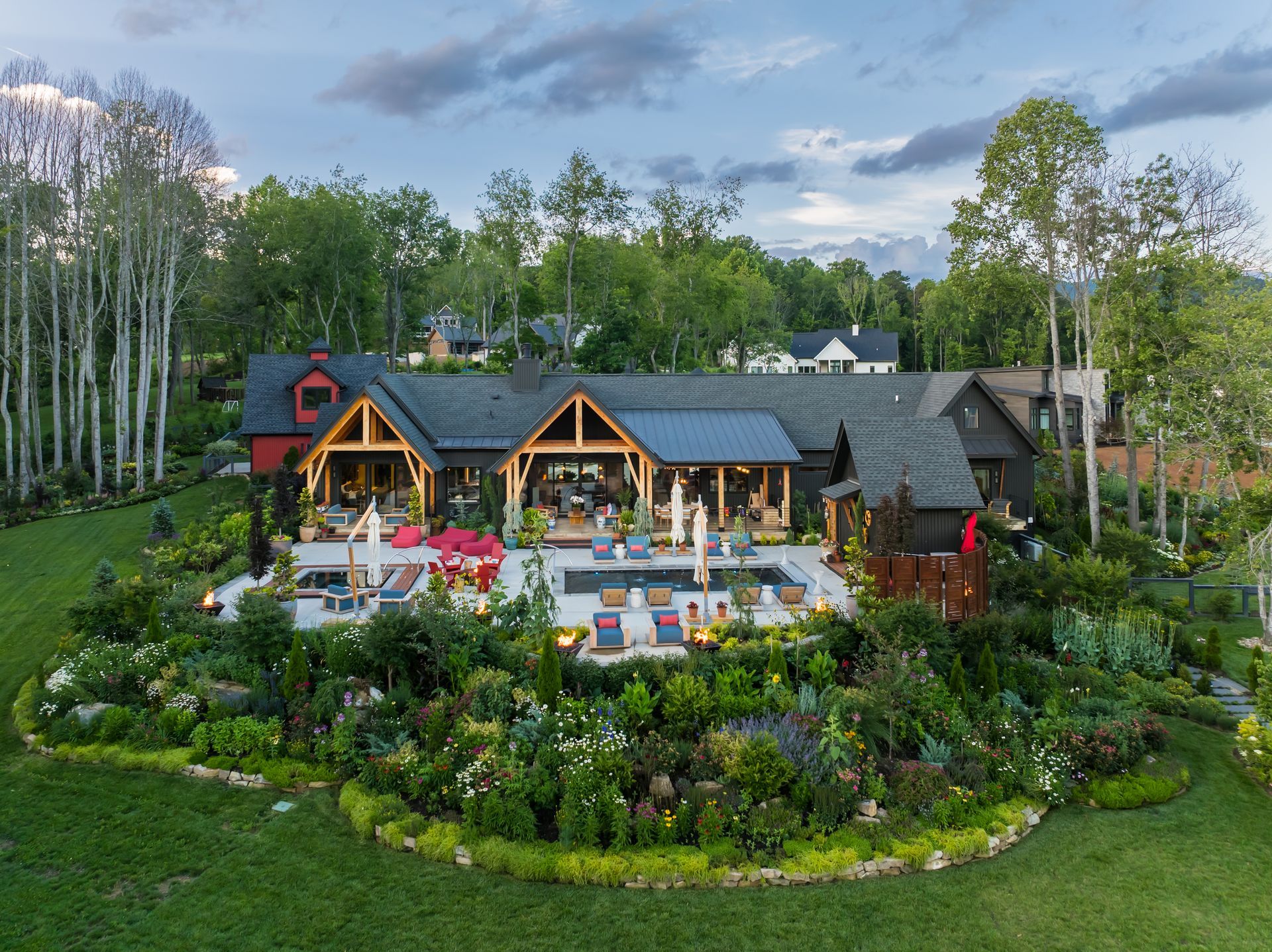 Elegant garden resort with a dark-roofed lodge, patio seating, and lush greenery at dusk
