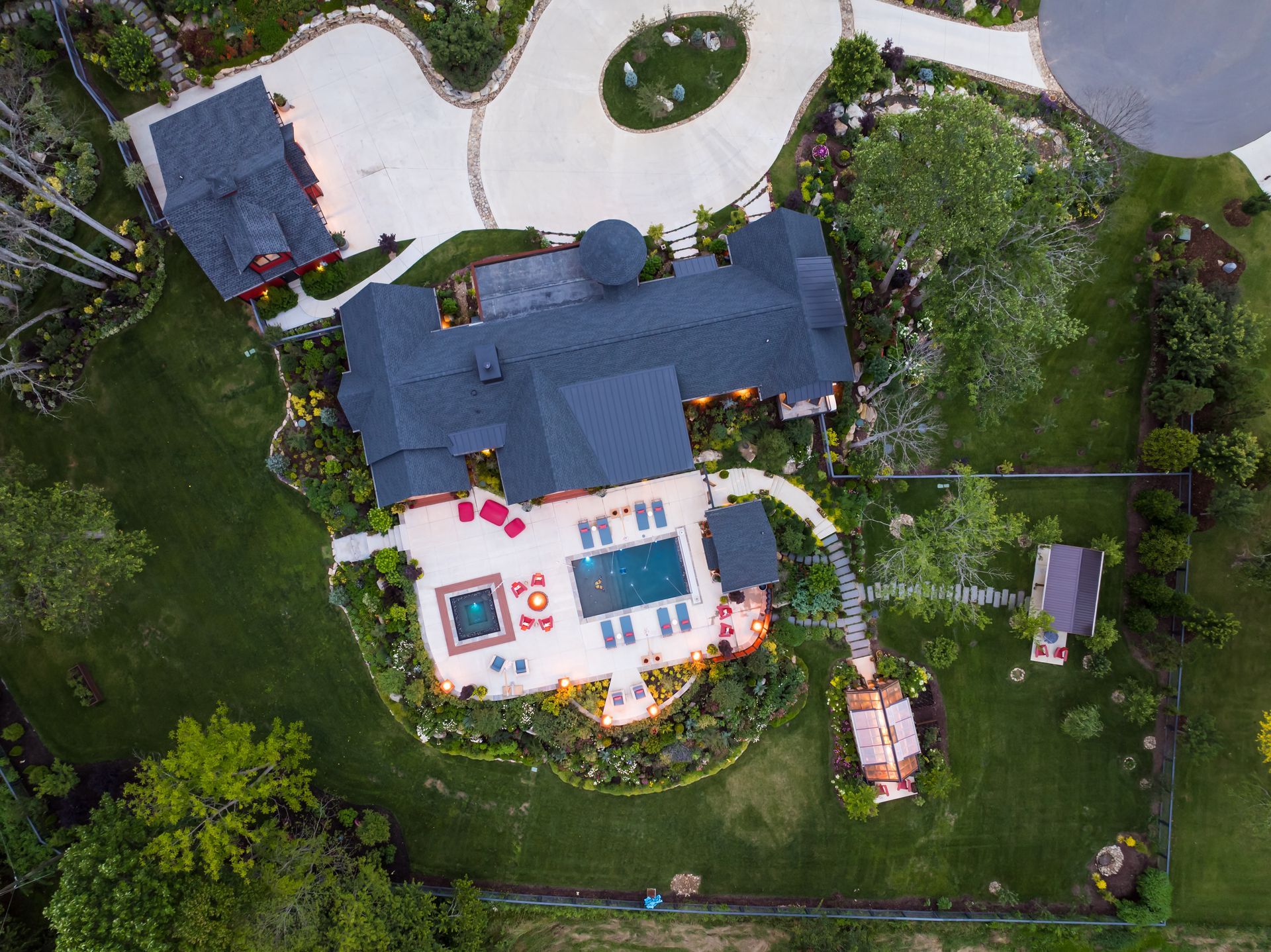 Aerial view of a house with a backyard pool, patio, and surrounding trees.
