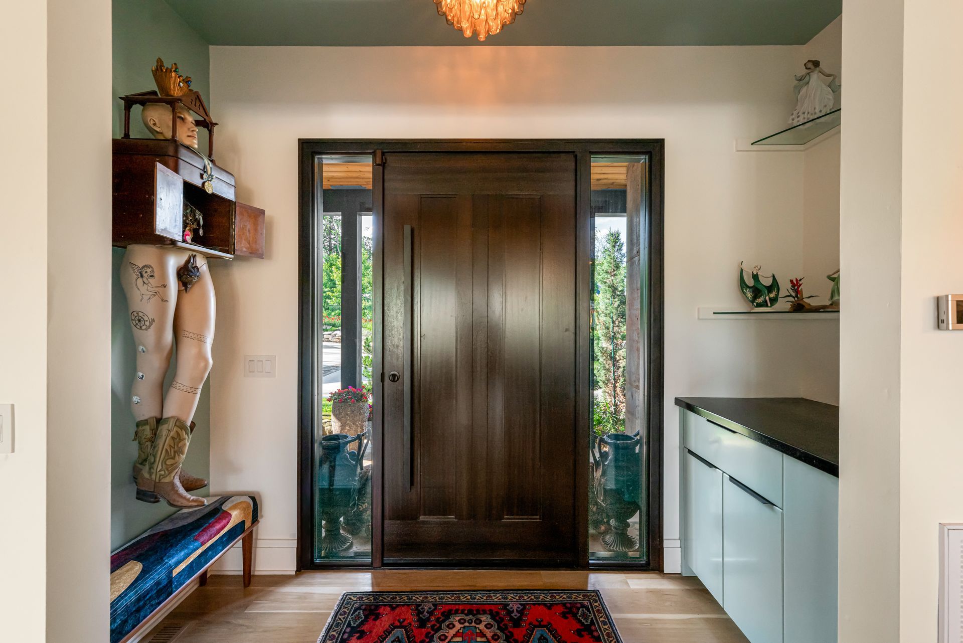 Entryway with dark wooden front door, sidelights, and a patterned runner rug; shelves and cabinets line the walls