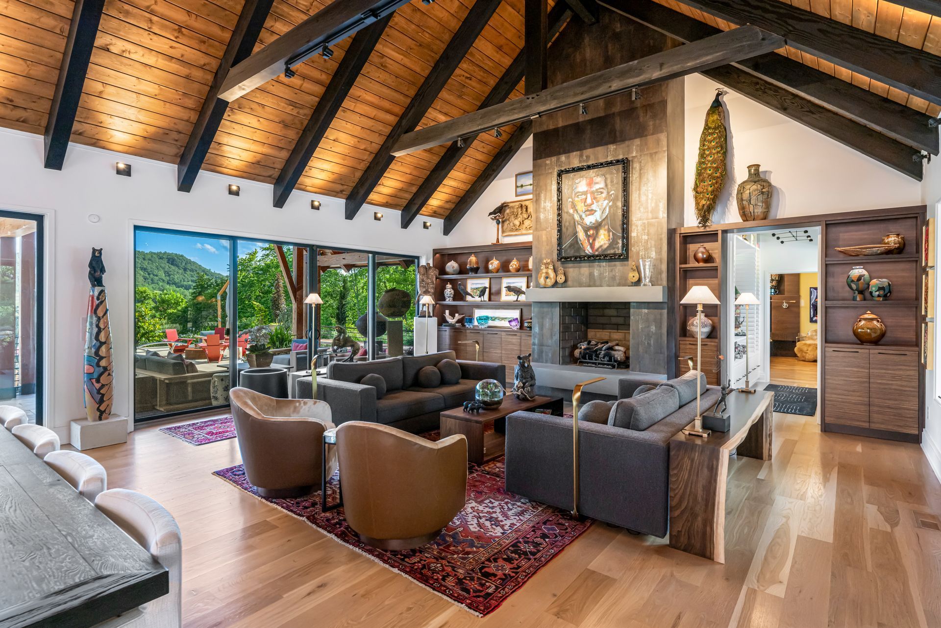Modern living room with vaulted wood ceiling, large windows, sofas, rug, and mountain view