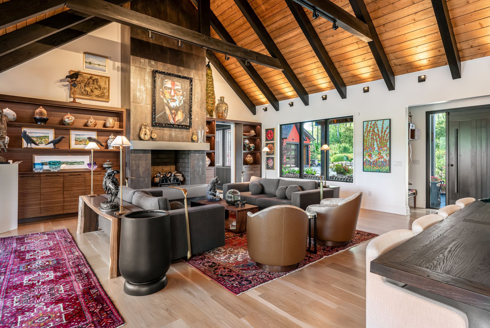Cozy living room with vaulted wood ceiling, fireplace, leather chairs, and large windows