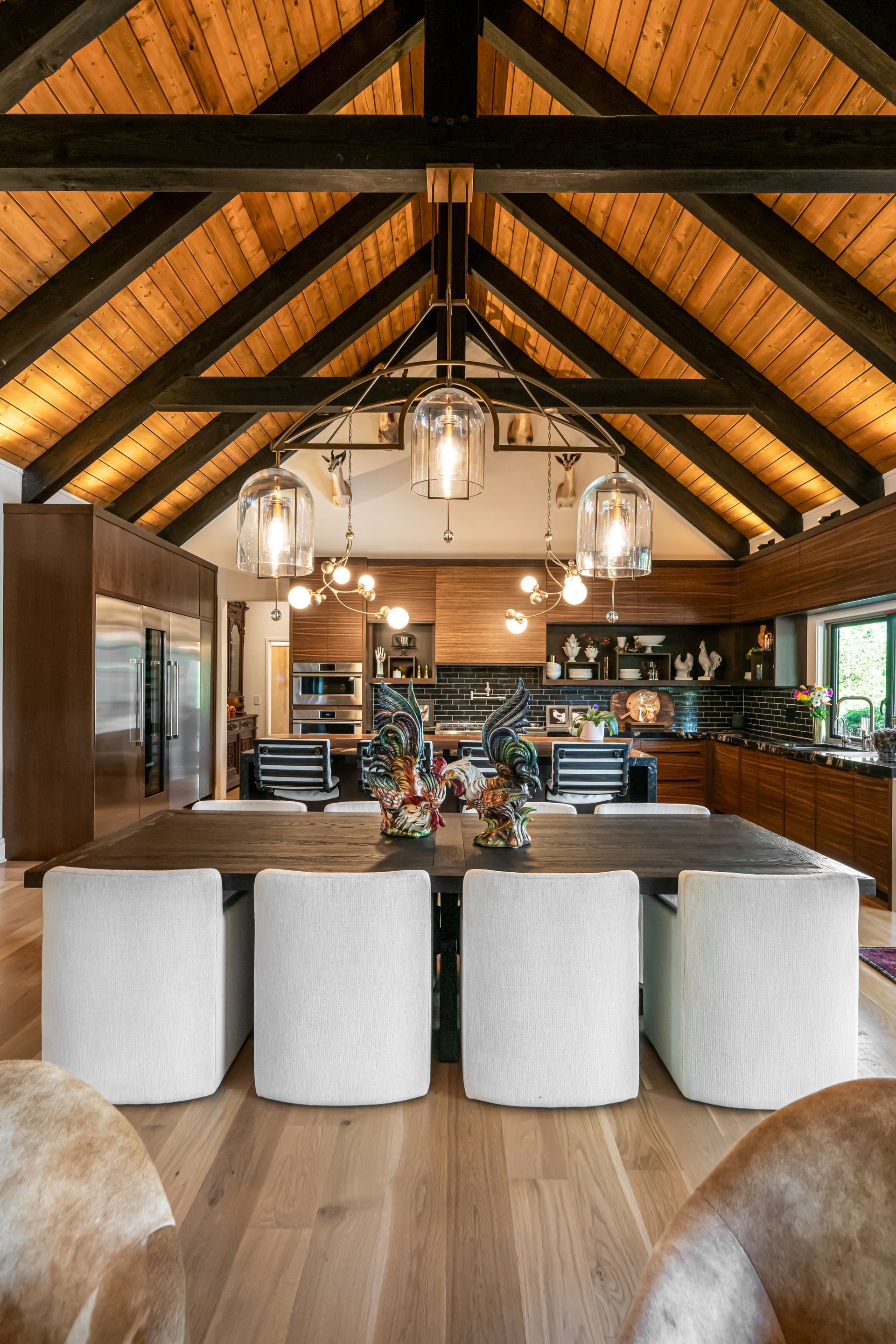 Rustic open-plan dining room with wood beams, large island stools, and warm pendant lighting
