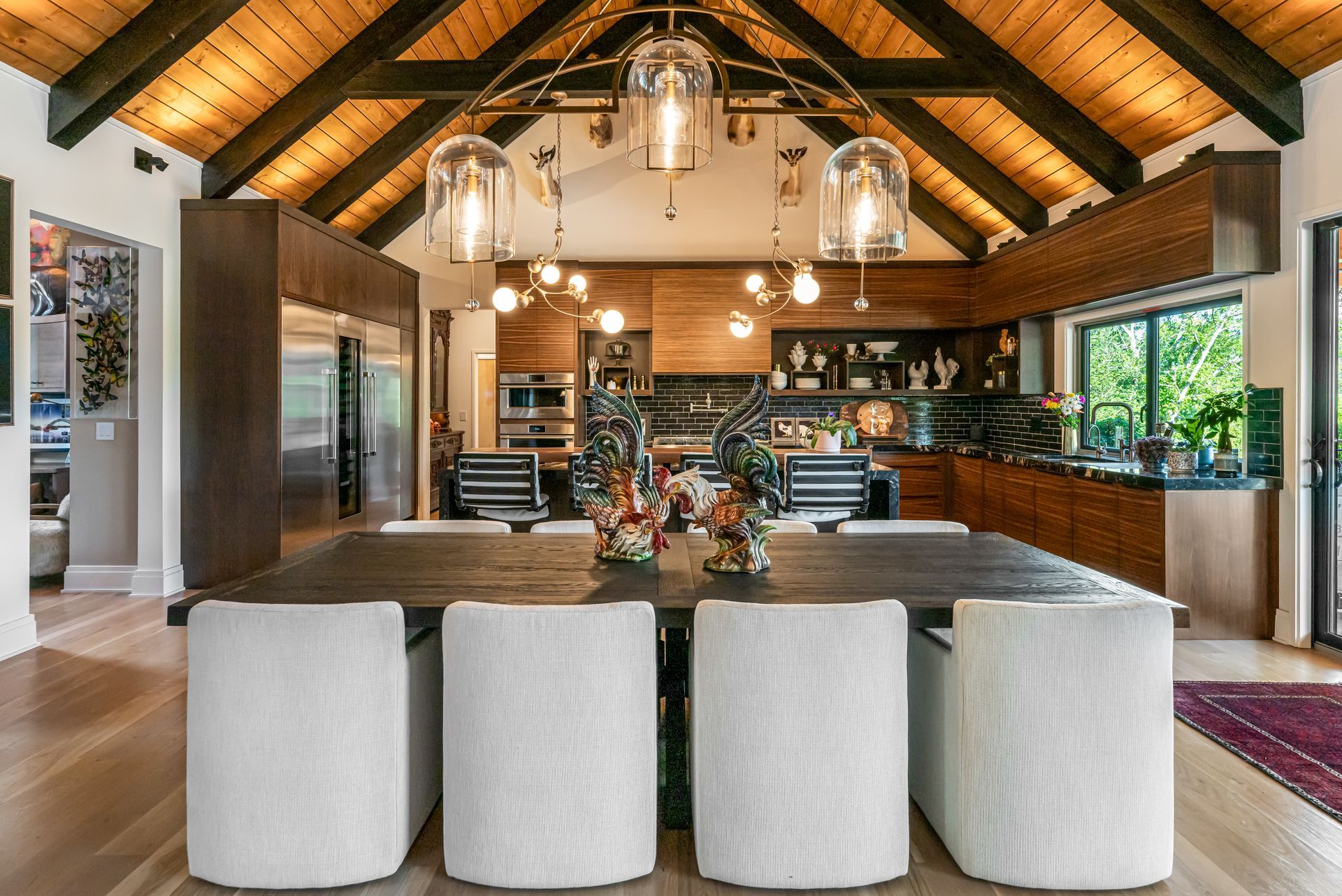 Spacious modern kitchen and dining area with vaulted wood ceiling, island seating, and hanging pendant lights