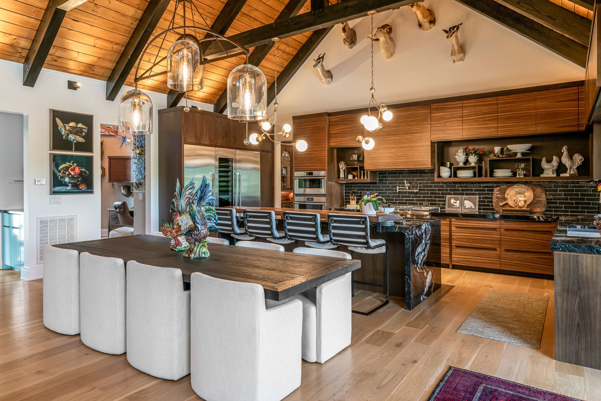 Modern open kitchen and dining area with exposed wood beams, island seating, and warm rustic decor