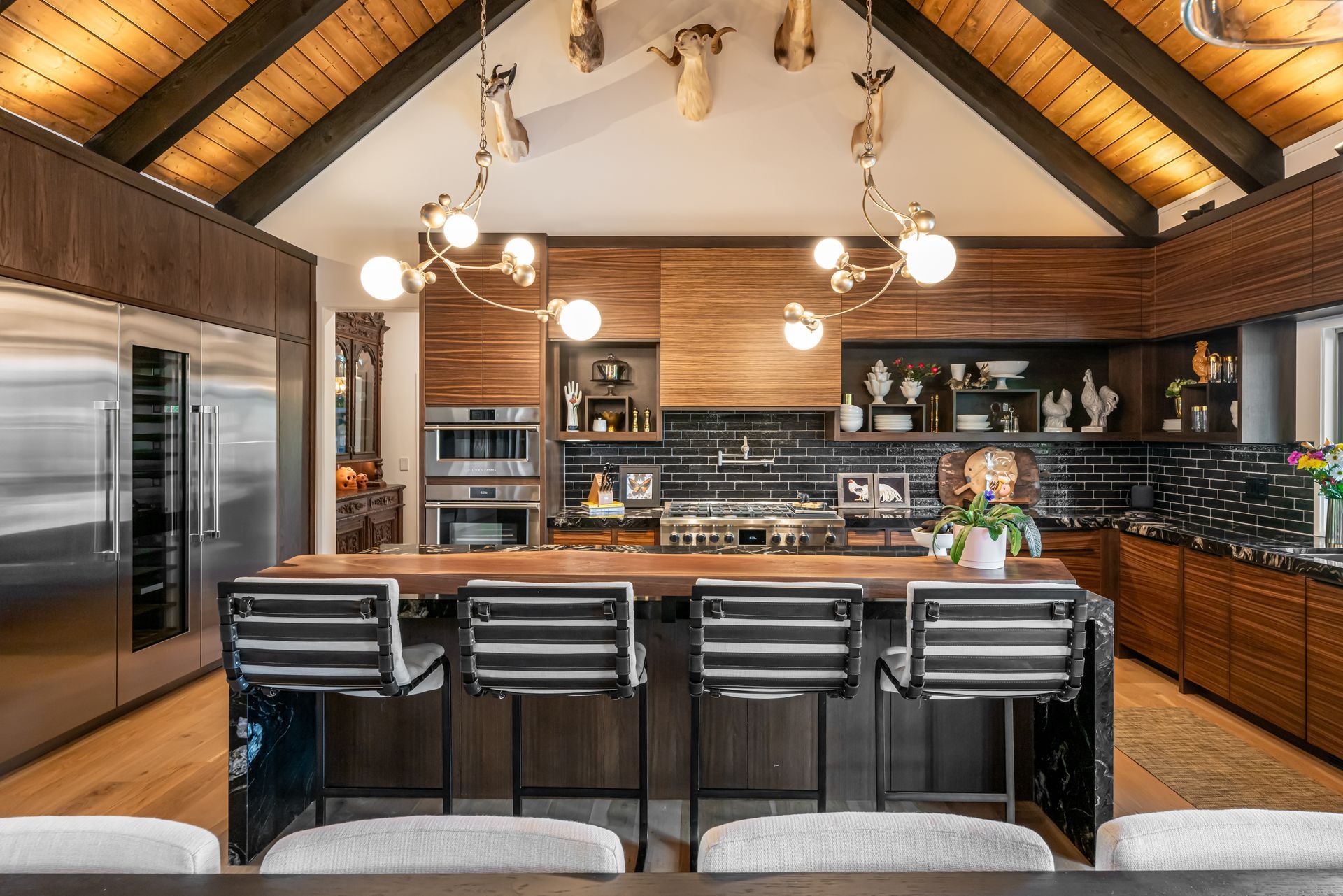 Modern kitchen with wood beams, black island stools, and a large stainless-steel refrigerator