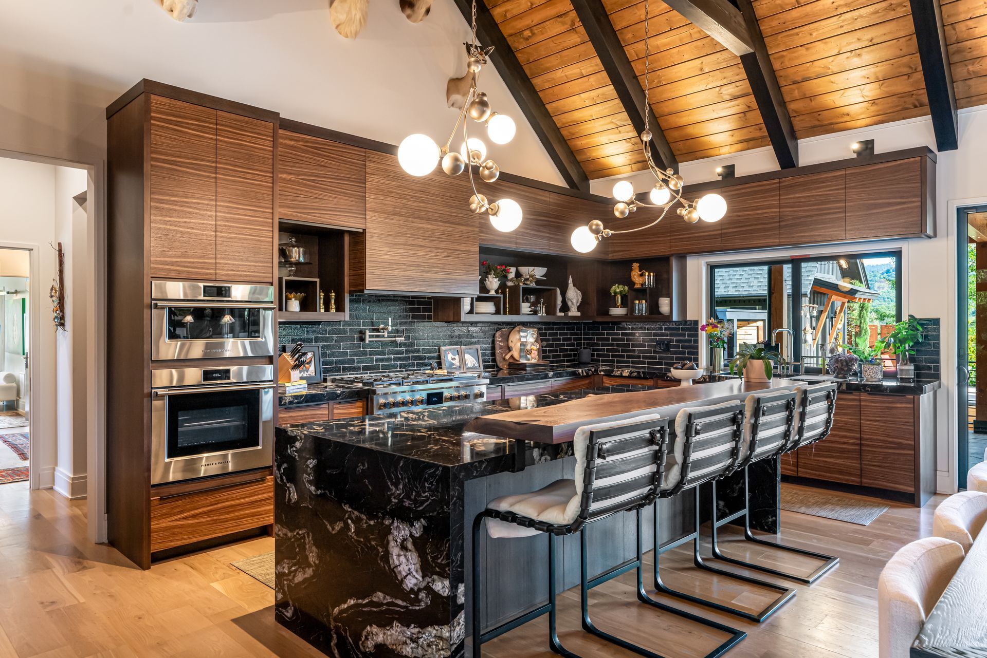 Modern kitchen with dark wood cabinets, black granite island, bar stools, and vaulted wood-beamed ceiling