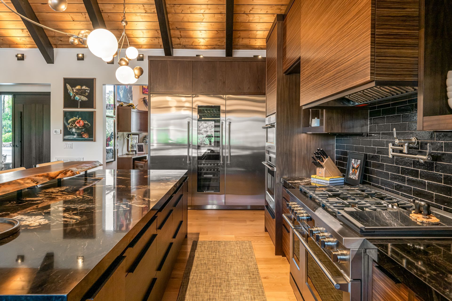 Modern kitchen with stainless steel appliances, dark granite counters, and warm wood finishes