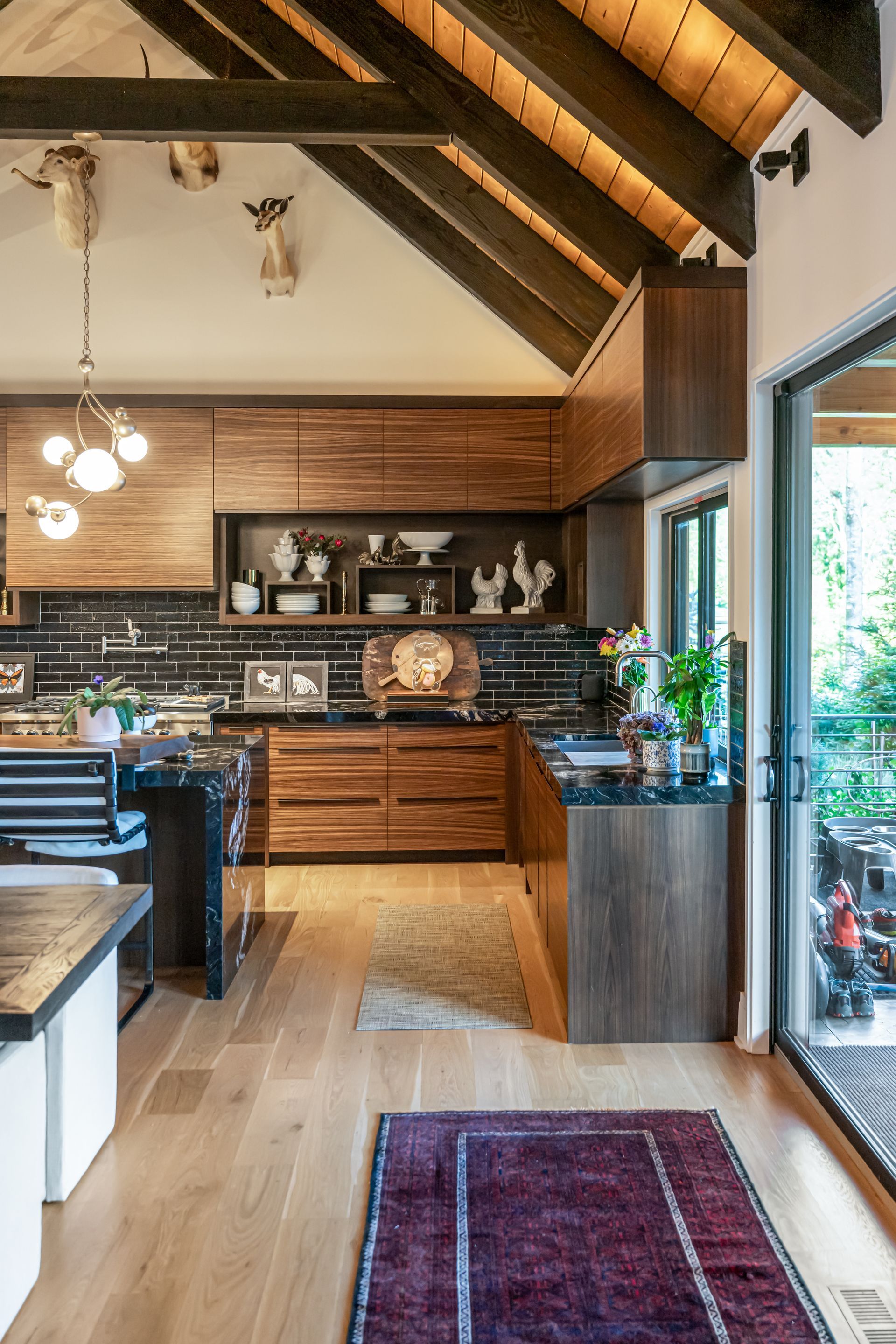 Modern kitchen and dining area with wood beams, dark cabinets, and a red runner rug