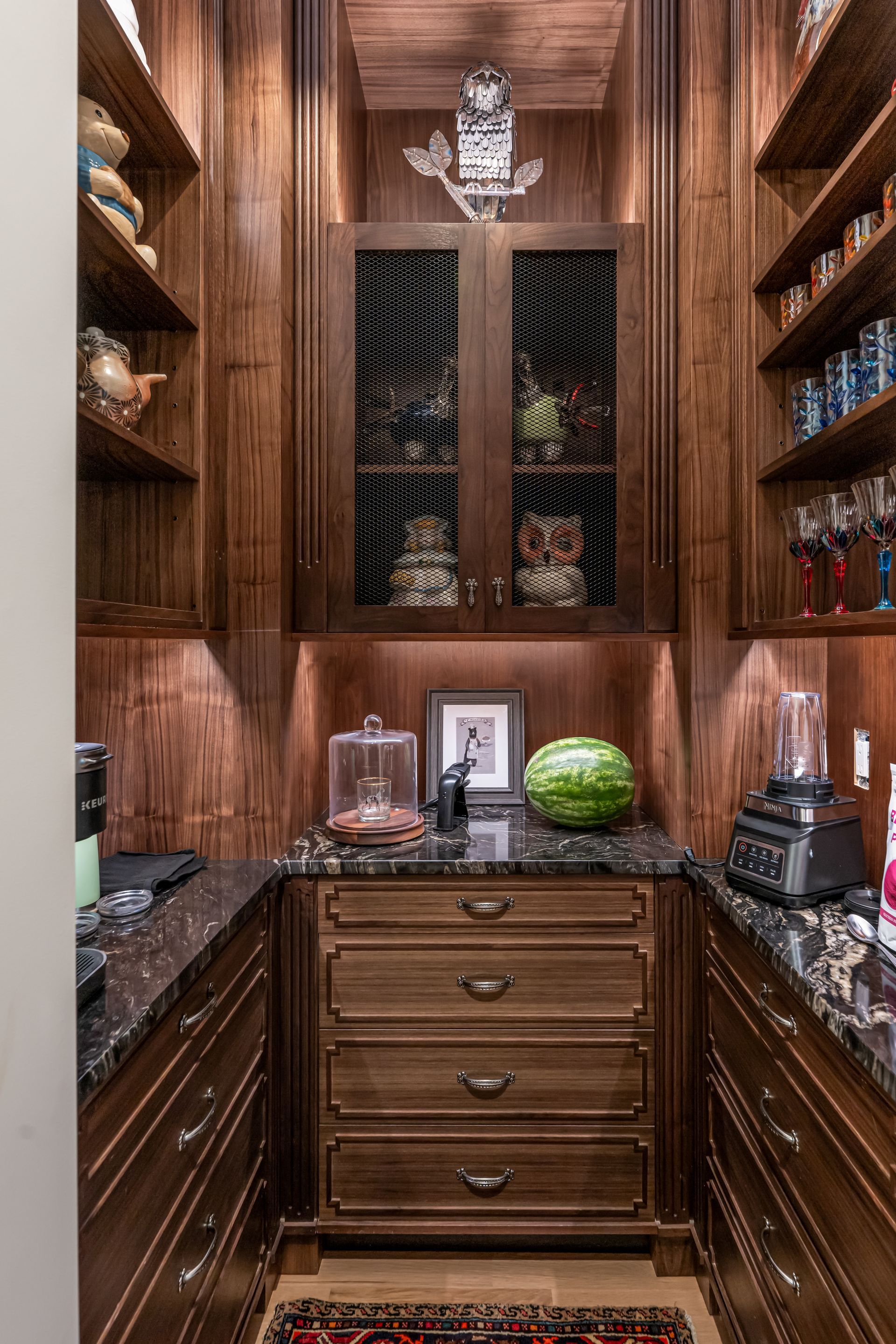 Wood-paneled wine cellar with built-in racks, marble countertops, and a central cabinet.