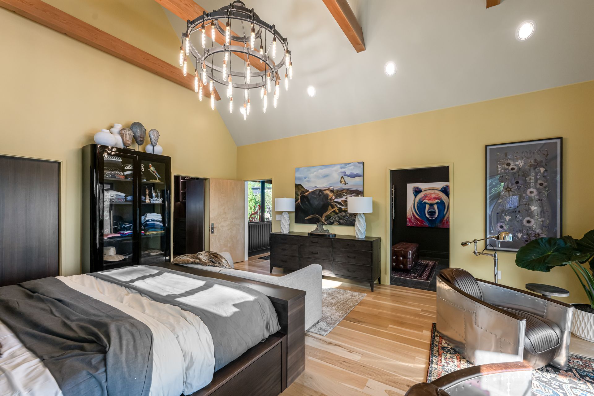 Modern bedroom with vaulted wood ceiling, black bed, TV console, and Chicago Cubs wall decor