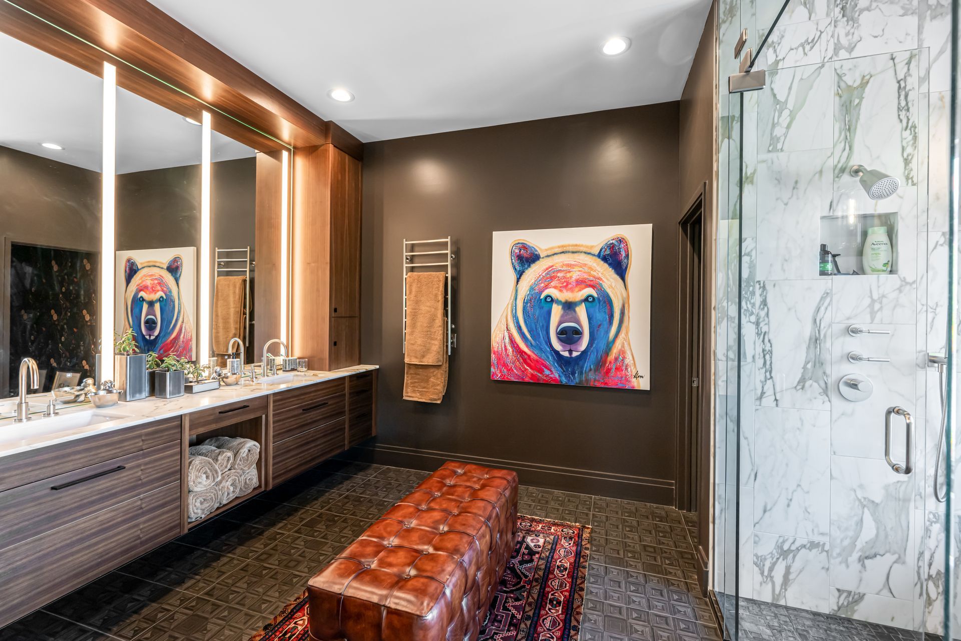 Modern bathroom with double vanity, bench, glass shower, and colorful bear artwork on the wall