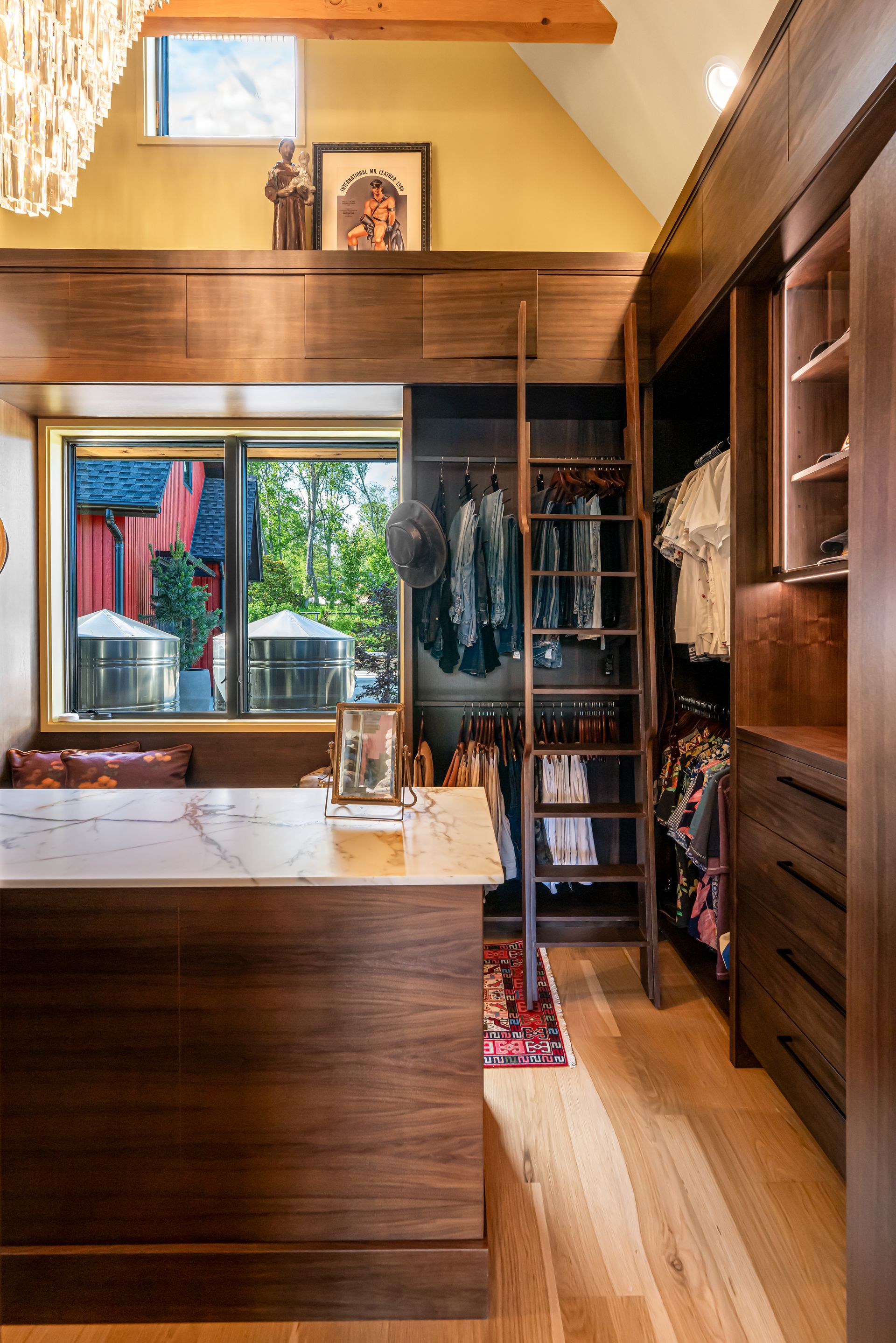 Bright kitchen with wooden cabinets, a central island, skylight, and large window overlooking a garden.