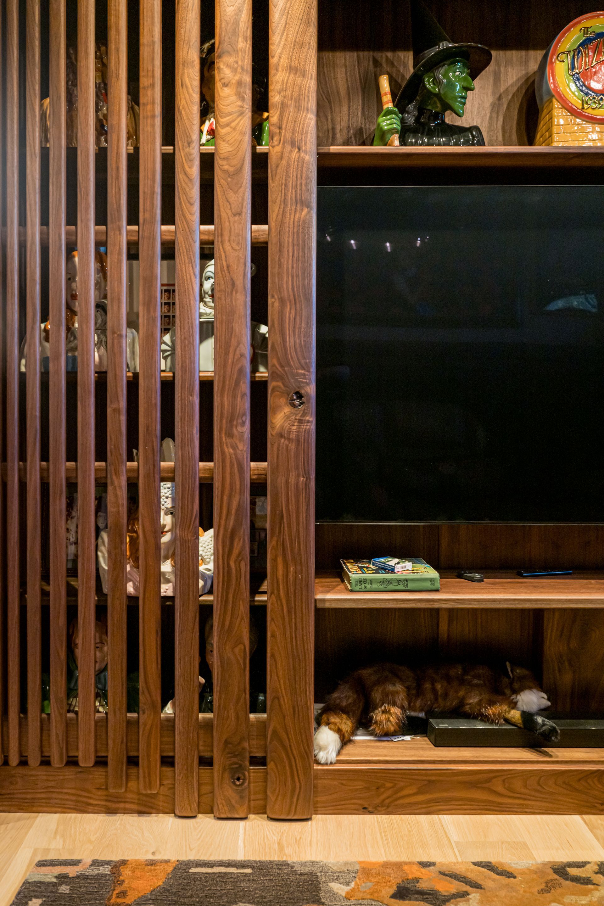 Wooden slatted partition beside a dark TV, with cats resting on a lower shelf in a home interior.