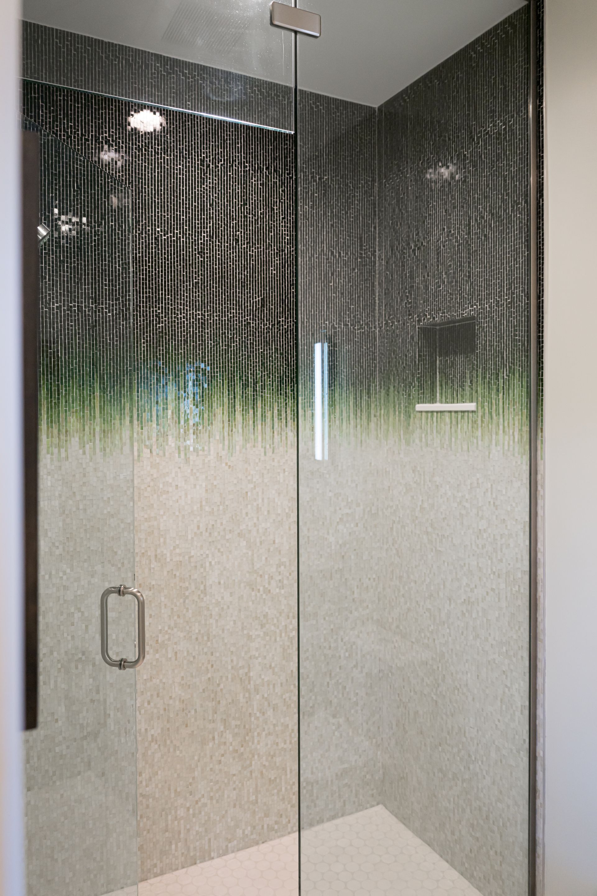 Modern glass shower stall with textured lower panels and a chrome handle