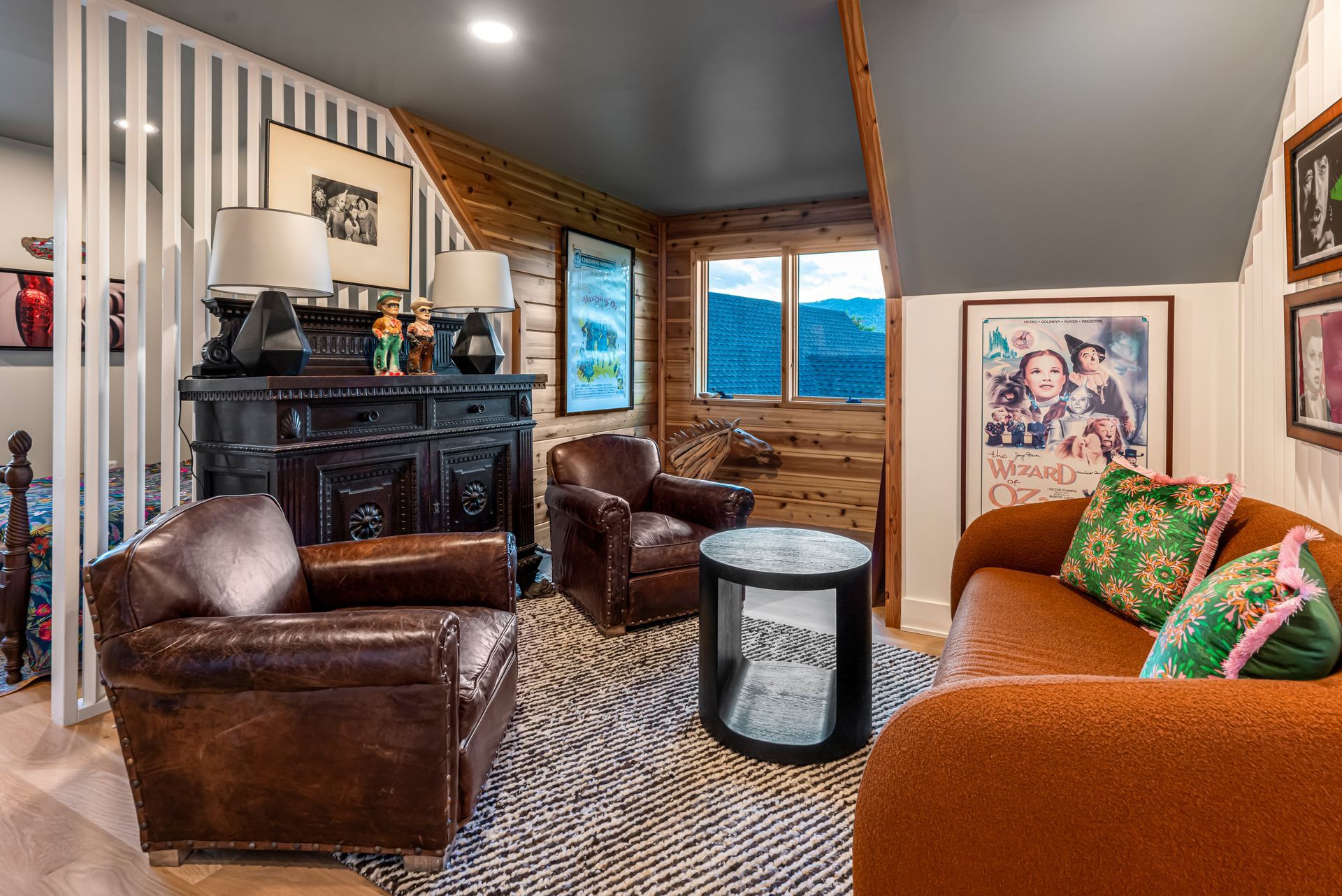 Cozy living room with leather chairs, orange sofa, patterned rug, and large windows overlooking snowy trees