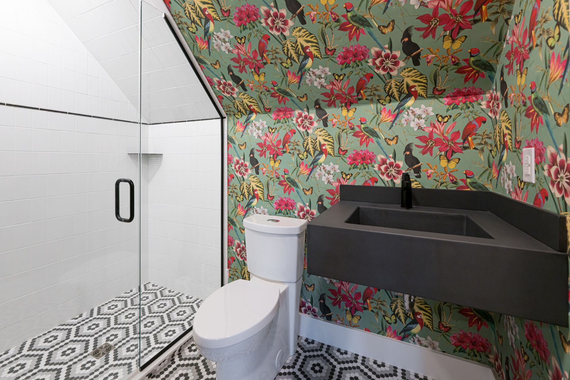 Small bathroom with floral wallpaper, black sink, white toilet, and patterned tile floor.