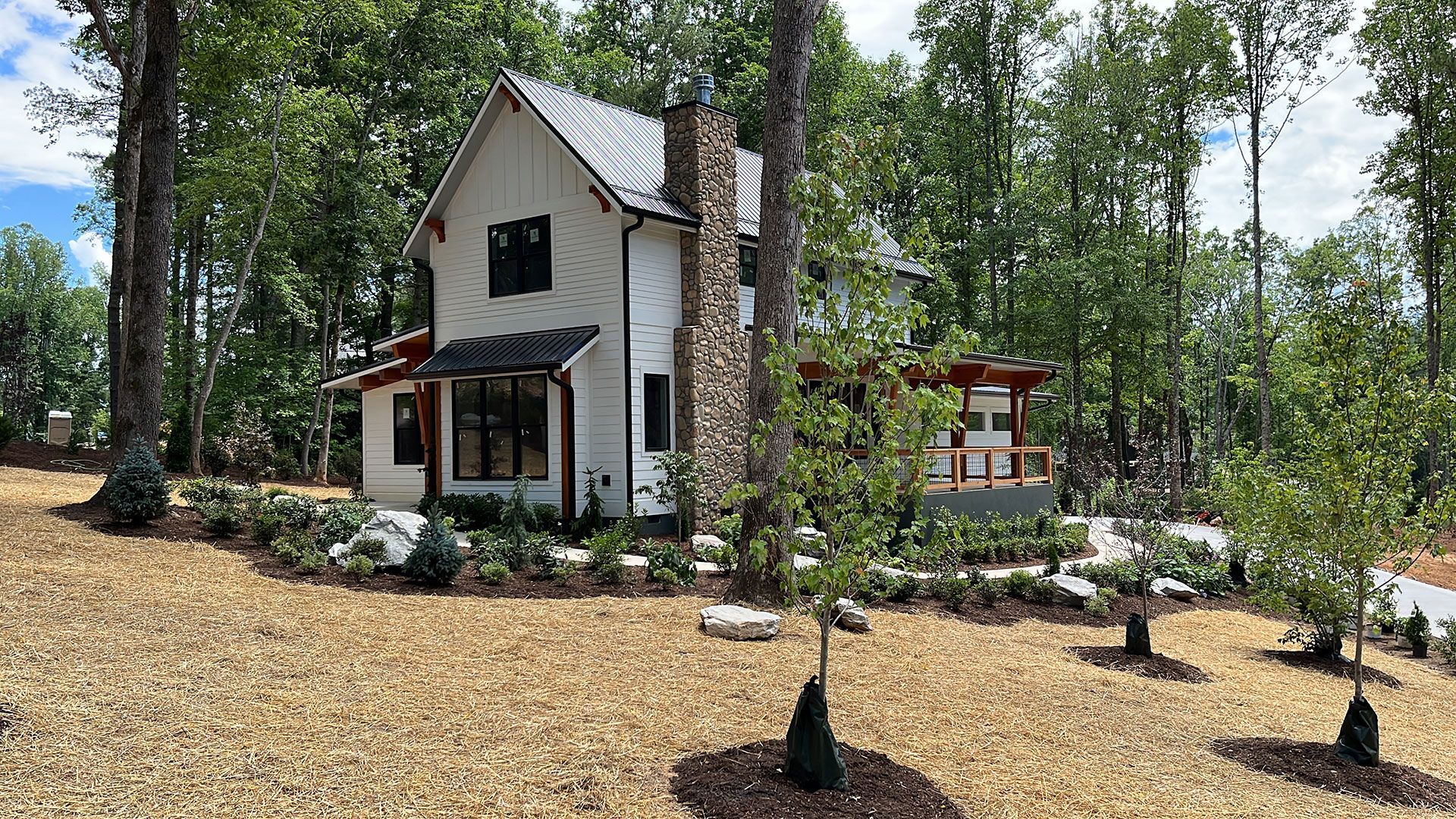 A white house is surrounded by trees in the middle of a forest.
