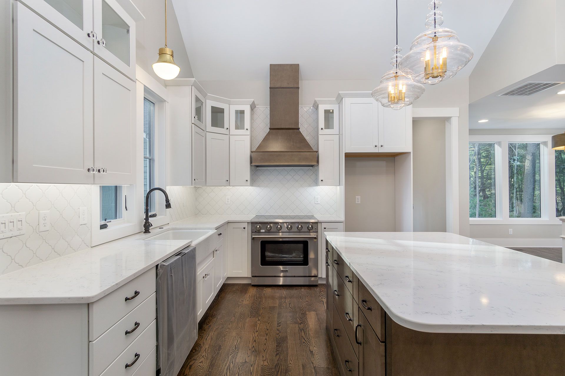 A kitchen with white cabinets, stainless steel appliances, and a large island.