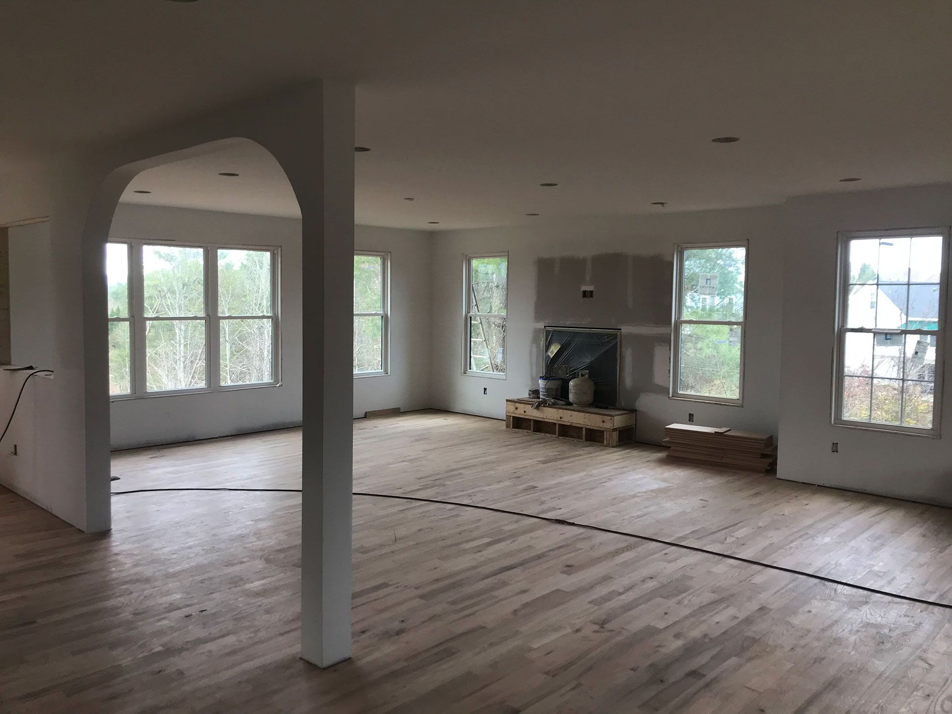 A large empty room with hardwood floors and white walls.