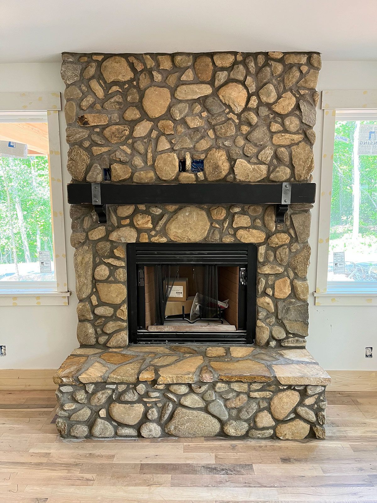 A stone fireplace with a black mantle in a living room.
