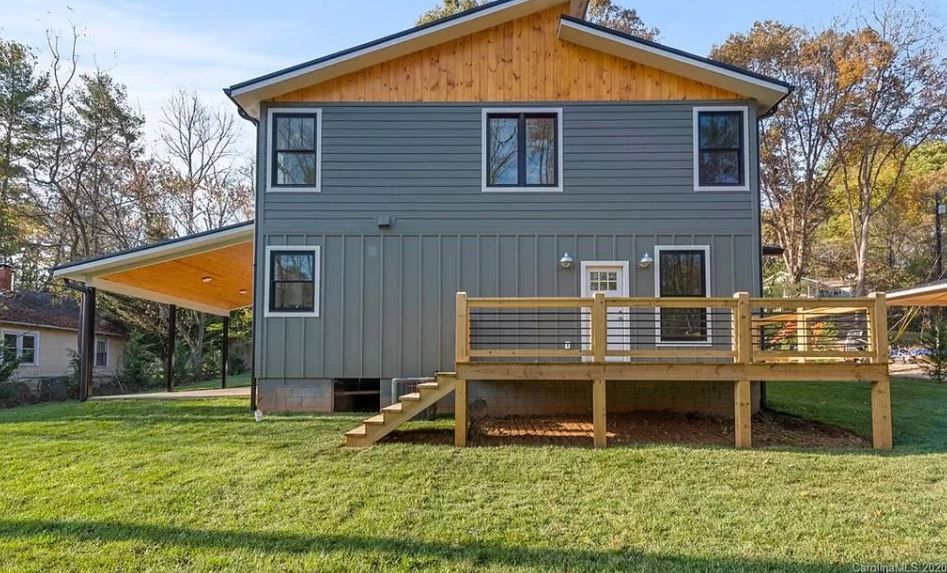 The back of a house with a wooden deck and stairs.