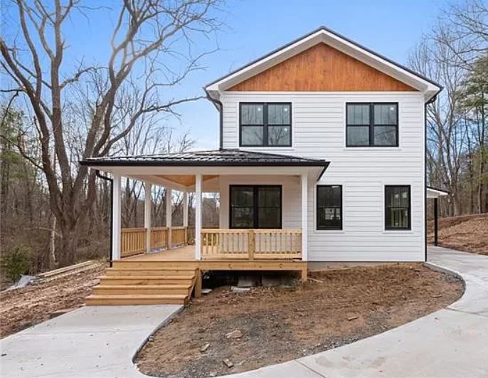 A white house with a wooden roof and a large porch.