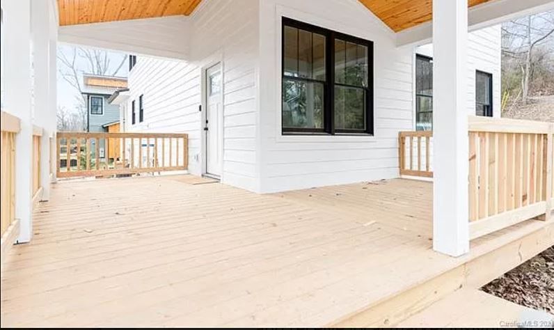 A white house with a wooden deck and a window.