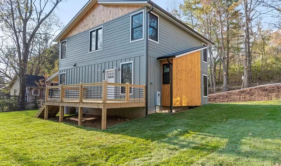 A small house with a deck and a shed in the backyard.