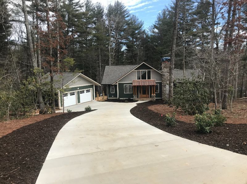 A driveway leading to a house in the middle of a forest.