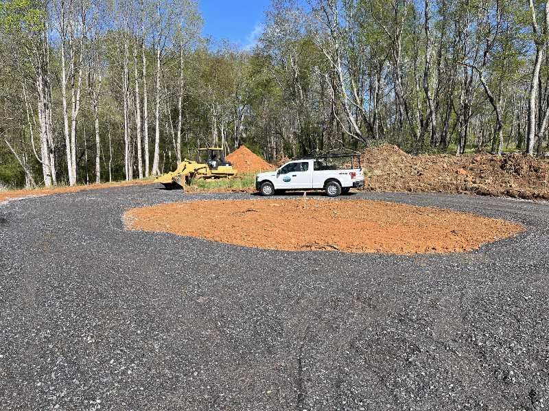 A white truck is parked on a gravel road next to a bulldozer.