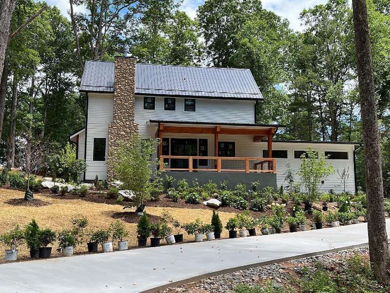 A white house is sitting on top of a hill surrounded by trees.