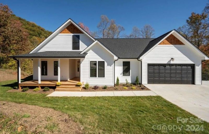 A white house with a black roof is for sale.