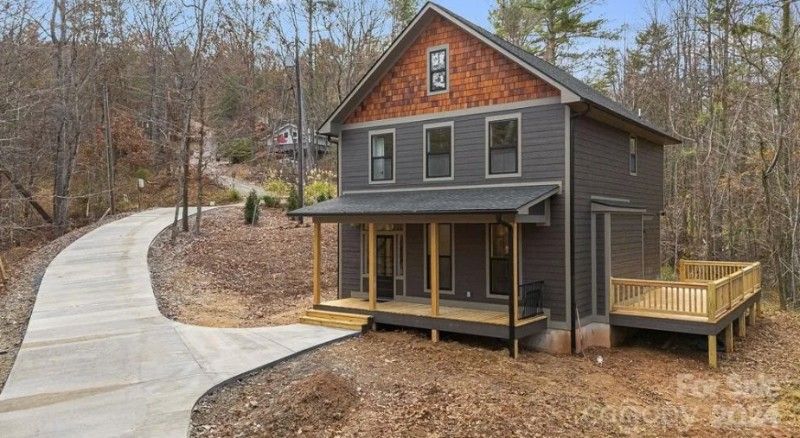 A small house with a porch and a driveway leading to it is for sale.