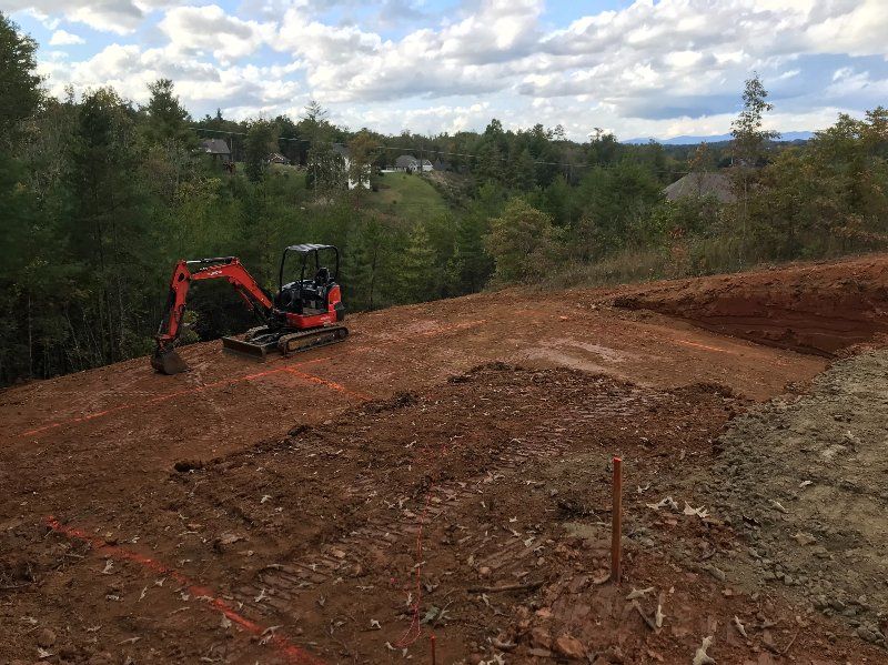 A small excavator is sitting on top of a dirt hill.