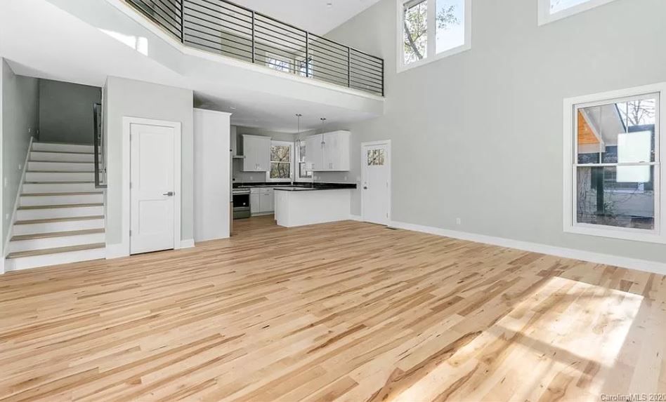 An empty living room with hardwood floors and a balcony.