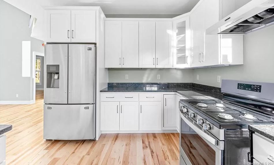 A kitchen with white cabinets, stainless steel appliances and hardwood floors.