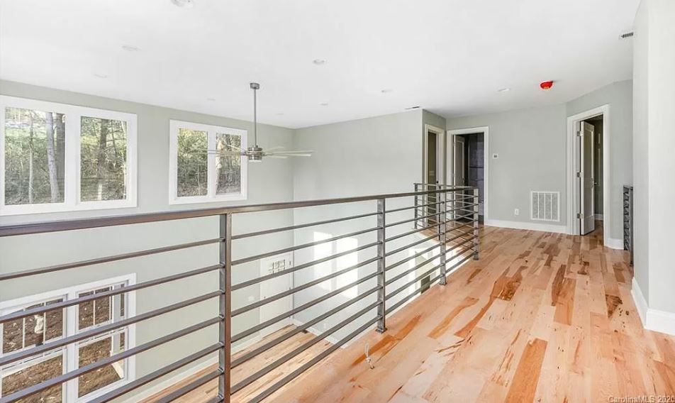 An empty room with hardwood floors and a metal railing.