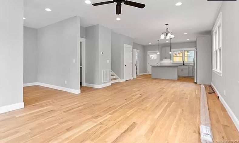 An empty living room with hardwood floors and a ceiling fan.