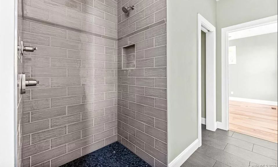 A bathroom with a walk in shower and a brick wall.