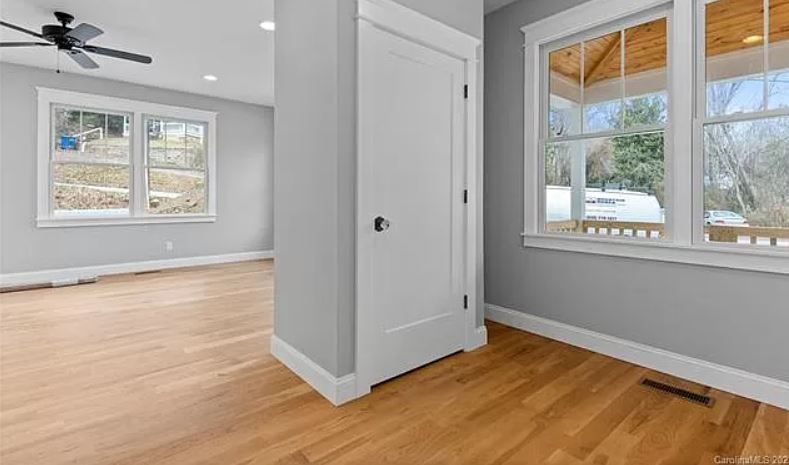 An empty room with hardwood floors and a ceiling fan.