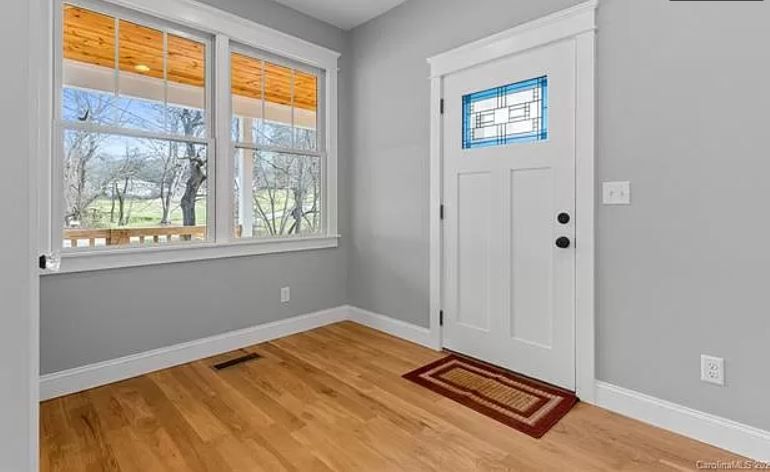 An empty room with hardwood floors and a white door.