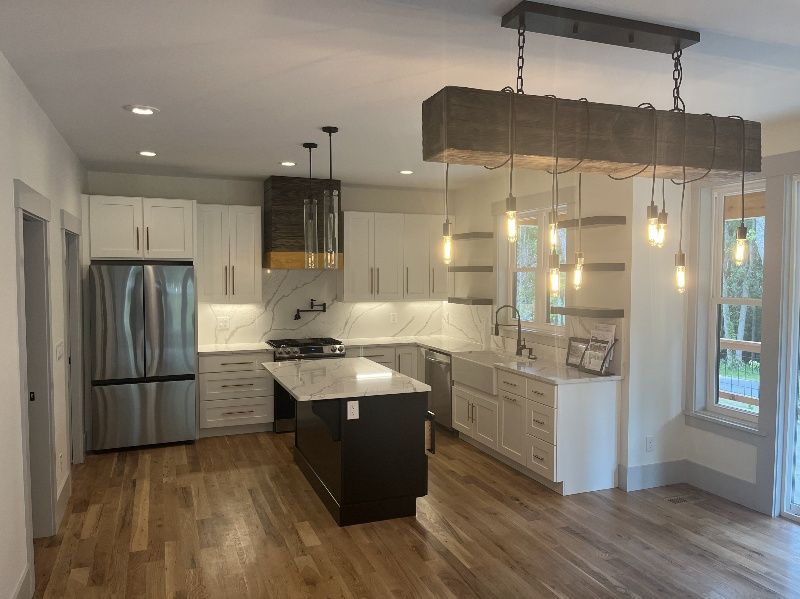 A kitchen with stainless steel appliances, white cabinets, hardwood floors and a large island.