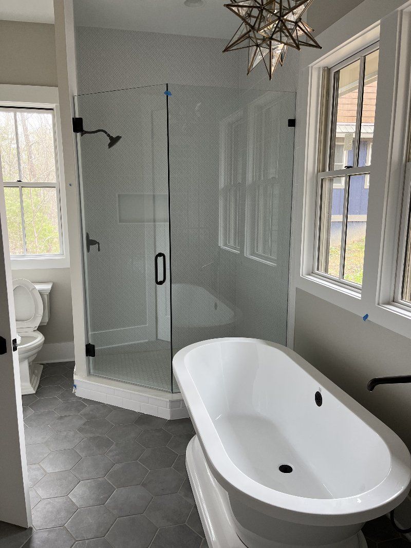 A bathroom with a tub, toilet, shower, and window.