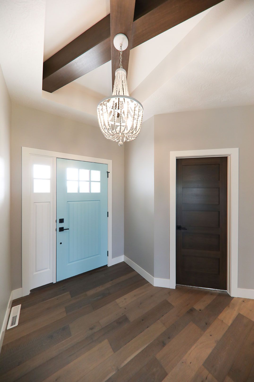 A hallway with a blue door and a chandelier hanging from the ceiling.