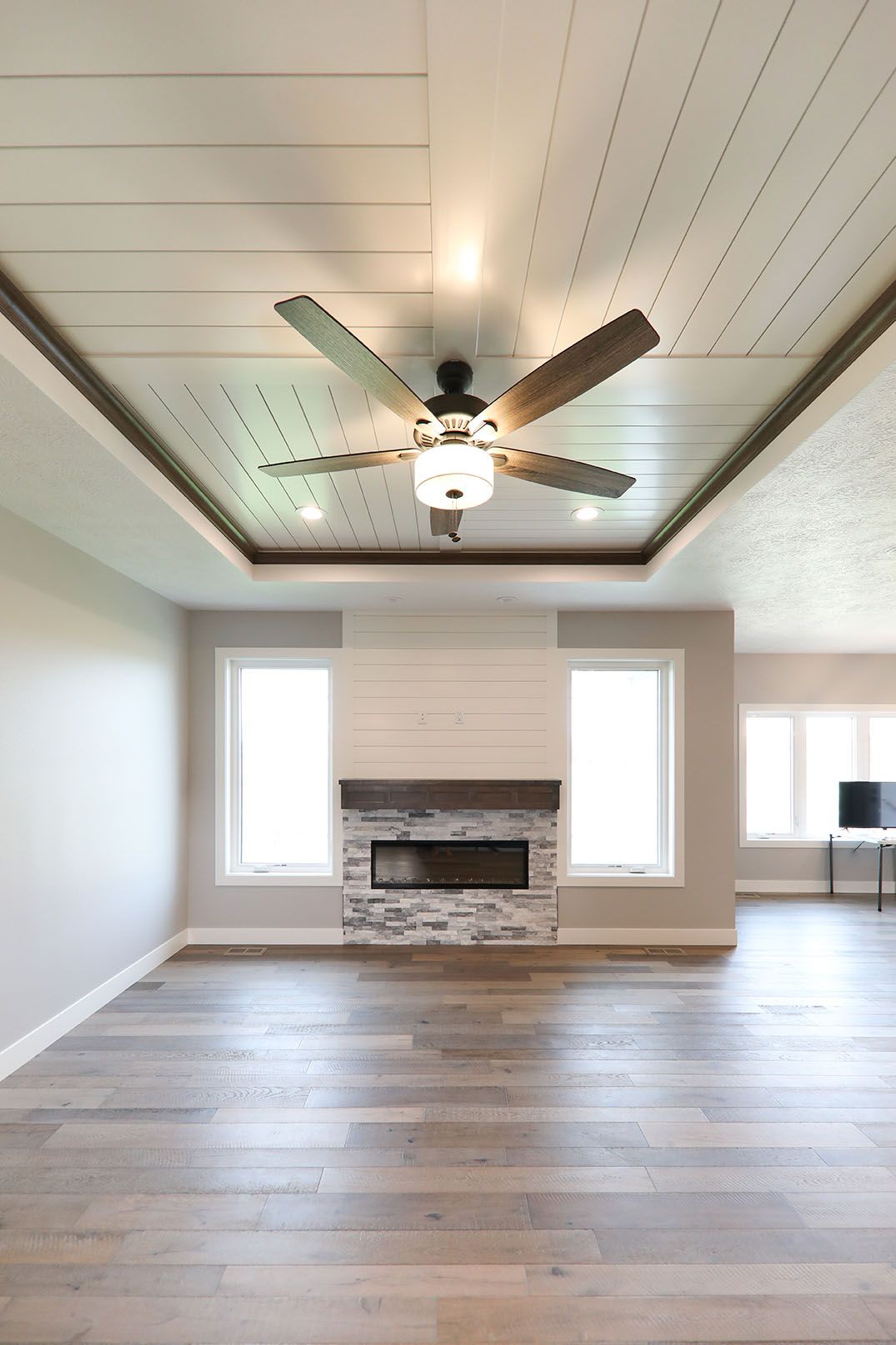 An empty living room with a fireplace and ceiling fan.